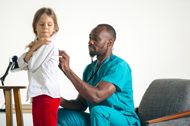 Cuidados de saúde e conceito médico - médico com estetoscópio, ouvindo o peito de criança no hospital