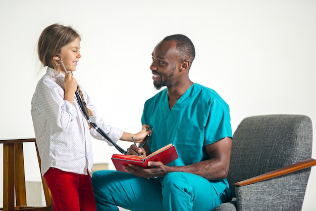 Cuidados de saúde e conceito médico - médico e menina com estetoscópio no hospital