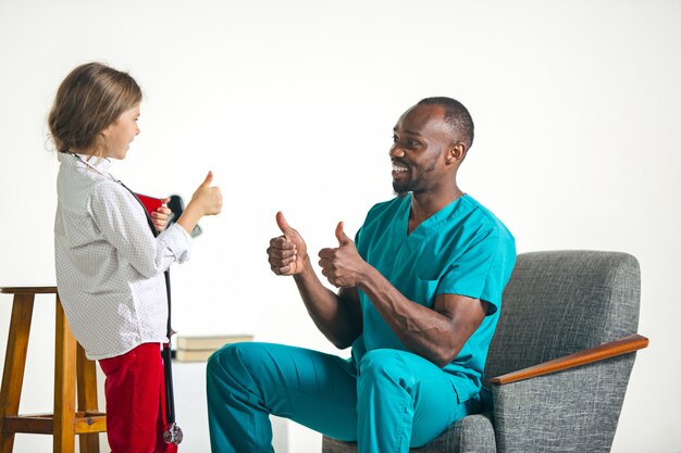 Cuidados de saúde e conceito médico - médico e menina com estetoscópio no hospital