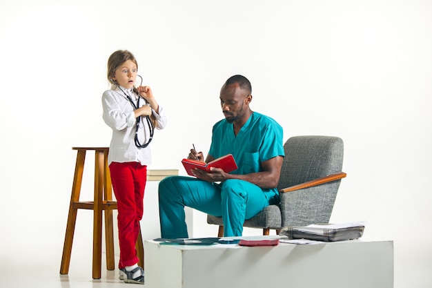 Cuidados de saúde e conceito médico - médico e menina com estetoscópio no hospital