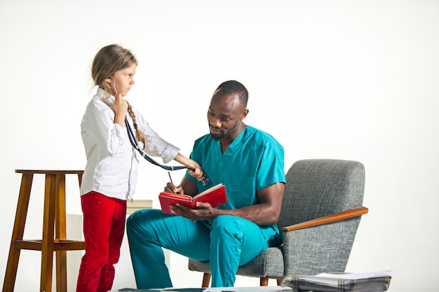 Cuidados de saúde e conceito médico - médico e menina com estetoscópio no hospital