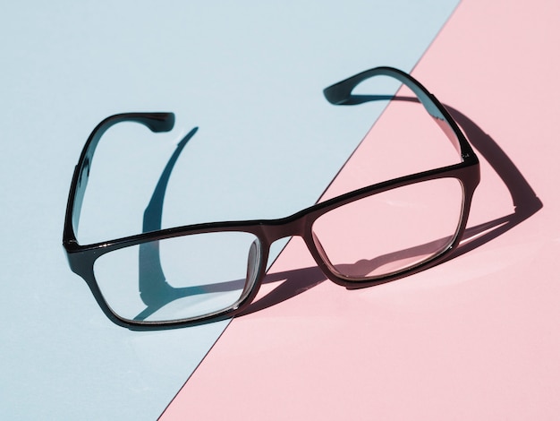 Óculos de armação preta sobre fundo azul e rosa