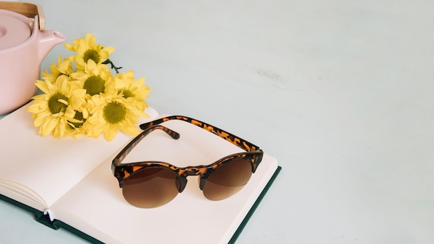 Óculos de sol e flores no caderno aberto