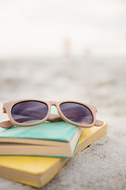 Óculos de sol e livros na areia