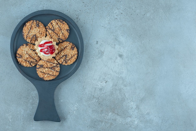 Foto grátis cupcake rodeado de biscoitos em uma pequena assadeira sobre superfície de mármore