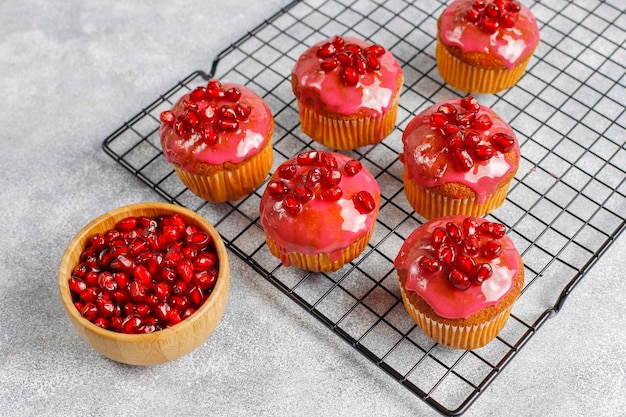 Cupcakes com cobertura e sementes de romã.