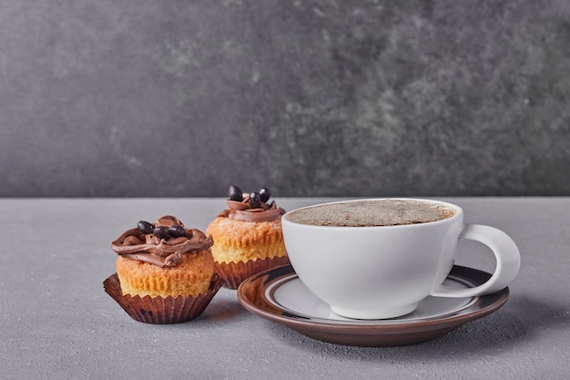 Cupcakes com creme de chocolate servidos com uma xícara de café.