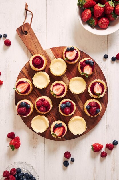 Cupcakes de queijo com geleia de frutas e frutas em um prato de madeira