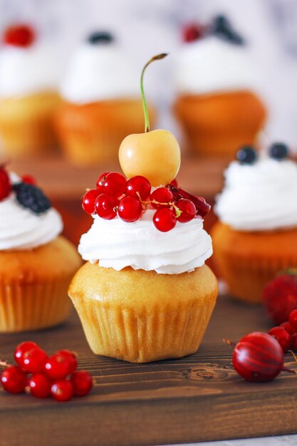 Cupcakes doces de baunilha com recheio de geléia de baga e creme de queijo, decorados com frutas de verão