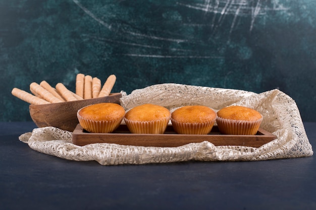 Cupcakes e waffles em uma travessa de madeira, vista angular