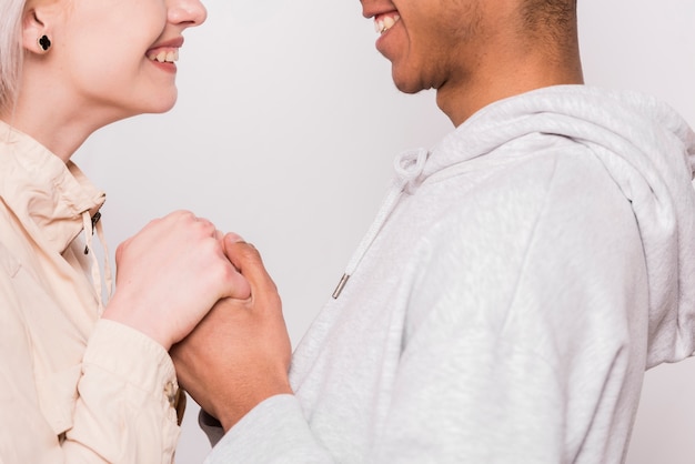 Cupê jovem interracial segurando a mão do outro isolado no fundo branco