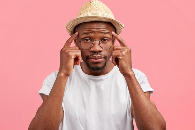 Curioso homem de meia-idade, pele escura, mantendo os dedos da frente nas têmporas