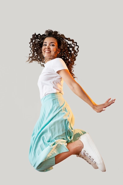 Foto grátis curly mulher pulando no estúdio