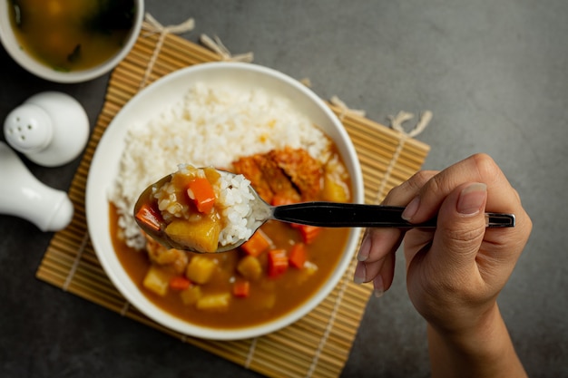 Curry de costeleta de porco frito com arroz na superfície escura