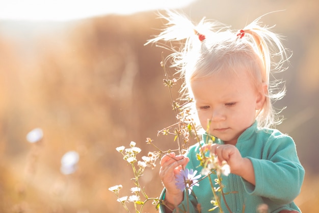 Foto grátis cute e doce menina brincando com flores ao ar livre