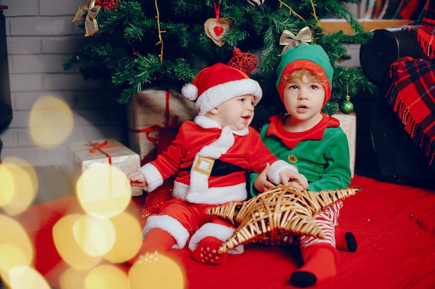 Cutte irmãozinhos em casa perto de decorações de natal