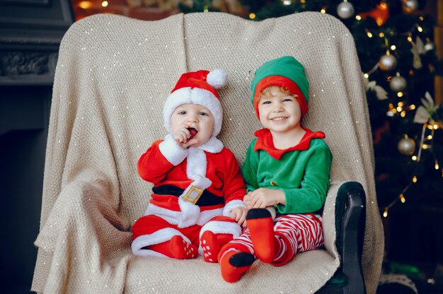 Cutte irmãozinhos em casa perto de decorações de natal
