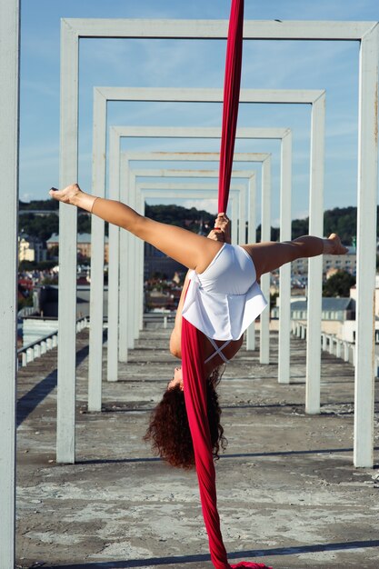 Dança aérea no telhado, dançarina de seda morena sexy em vestido branco