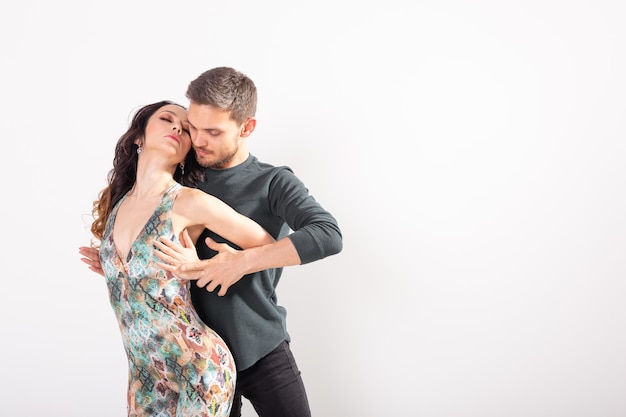 Dança social, kizomba, tango, salsa, conceito de pessoas - lindo casal dançando bachata no fundo branco com espaço de cópia