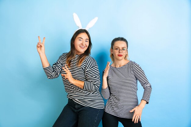 Dançando juntos. Jovens mulheres emocionais isoladas em fundo gradiente de estúdio azul. Conceito de emoções humanas, expressão facial, amizade, anúncio. Lindos modelos femininos caucasianos com roupas casuais.