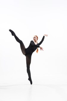Dançarina de balé jovem e graciosa no estilo preto mínimo, isolado no fundo branco do estúdio