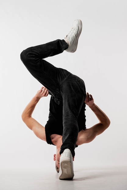 Dançarino em jeans e tênis posando com o corpo torcido