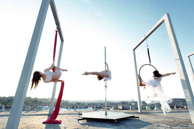 Dançarinos atléticos que executam dança aérea e de poste no telhado