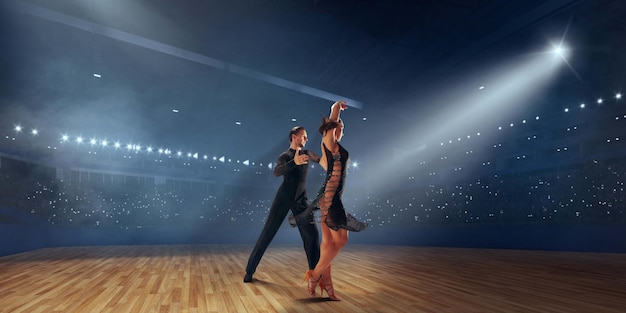 Dançarinos de casal realizam dança latina em grande palco profissional dança de salão