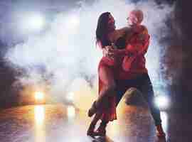 Foto grátis dançarinos hábeis, realizando no quarto escuro sob a luz do concerto e fumaça. casal sensual realizando uma dança contemporânea artística e emocional