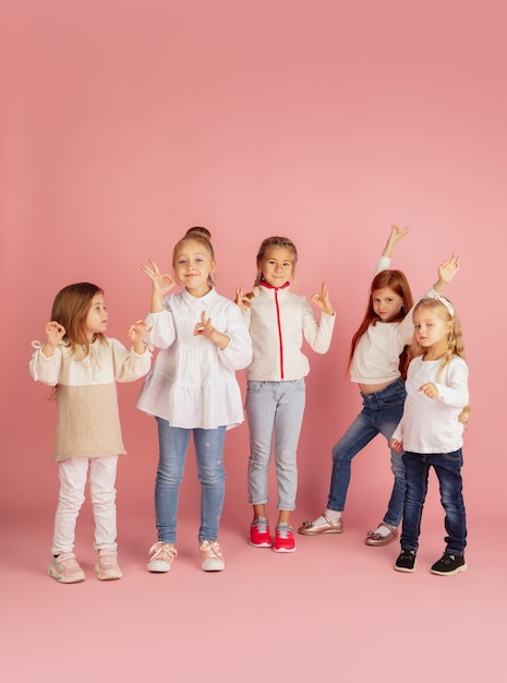 Dar e ganhar presentes nas férias de Natal. Grupo de crianças felizes e sorridentes, se divertindo, comemorando isolado no fundo rosa do estúdio. Encontro de ano novo 2021, infância, felicidade, emoções.