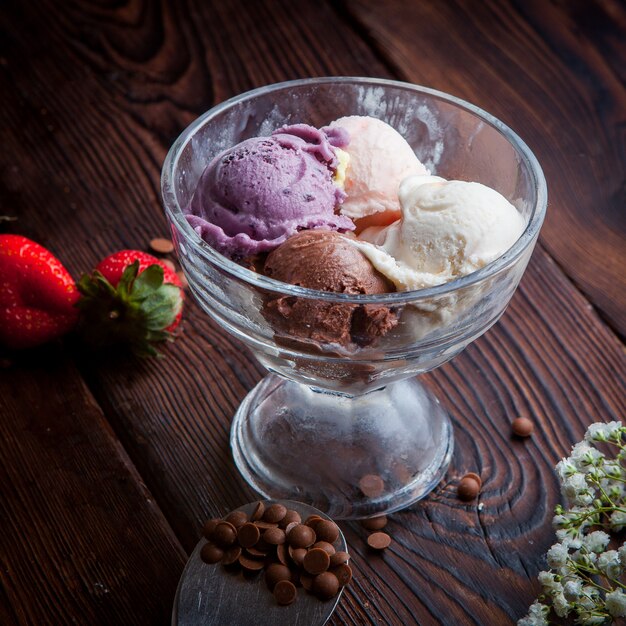 De cima bolas de sorvete com gotas de chocolate e morango e gypsophila em xícara de sorvete