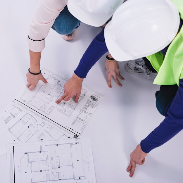 Foto grátis de cima construtores discutindo plantas