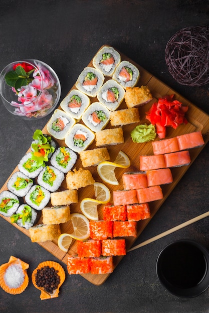 De cima do conjunto de sushi com molho de soja e os pauzinhos na tábua de madeira