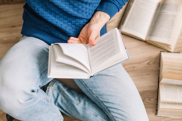 De cima homem lendo livro no chão