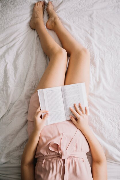 De cima mulher lendo livro na cama