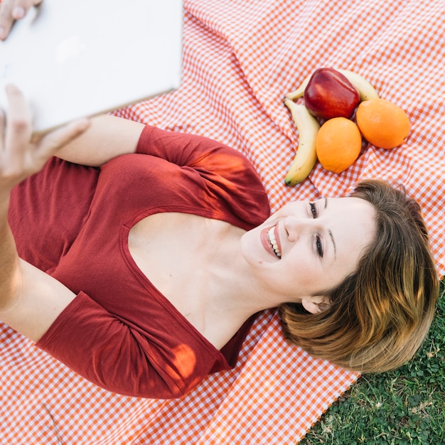 De cima mulher usando tablet perto de frutas