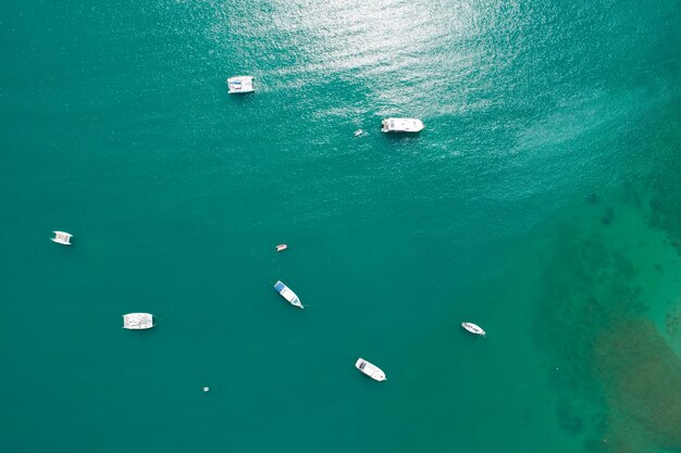 De cima para baixo, a câmera do drone de vista aérea do lindo mar de águas claras turquesa com barcos à vela no mar de verão ilha tropical de phuket do sul da tailândia.