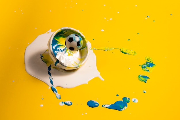 Decoração de alto ângulo com tinta amarela e bola de futebol