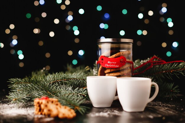 Decoração de ano novo e Natal. Garrafa com biscoitos de chocolate e xícaras para chá