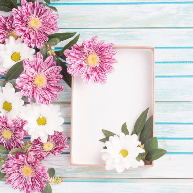 Decoração de flores com uma caixa vazia no pano de fundo de madeira