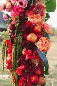 Decoração outonal em arco de casamento com rosas, maçãs, uvas e pomergranate