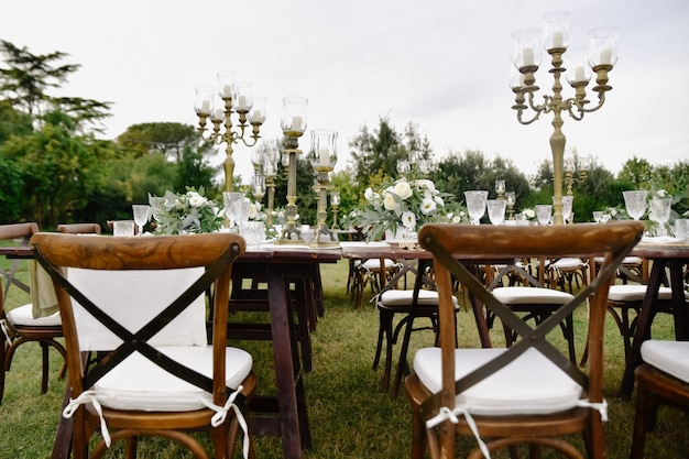 Decorado com composições florais, mesa de festa de casamento com cadeiras chiavari marrons, assentos dos hóspedes ao ar livre nos jardins