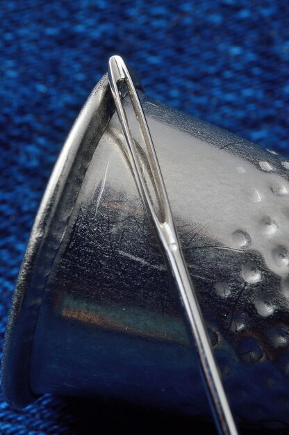 Dedal e agulha de costura em material azul. fechar-se. Foto Premium