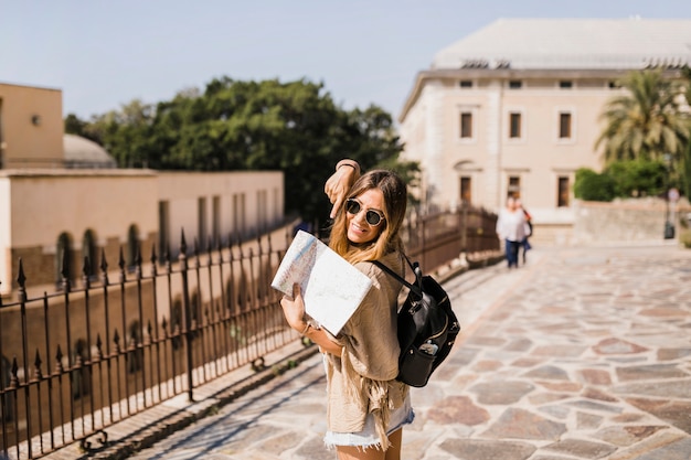 Dedo apontando elegante feminino turista no mapa