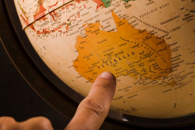Foto grátis dedo de uma pessoa apontando para o país da austrália na globo