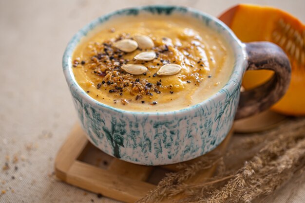 Deliciosa composição com sopa de abóbora em um lindo prato de cerâmica. Alimentos sazonais.