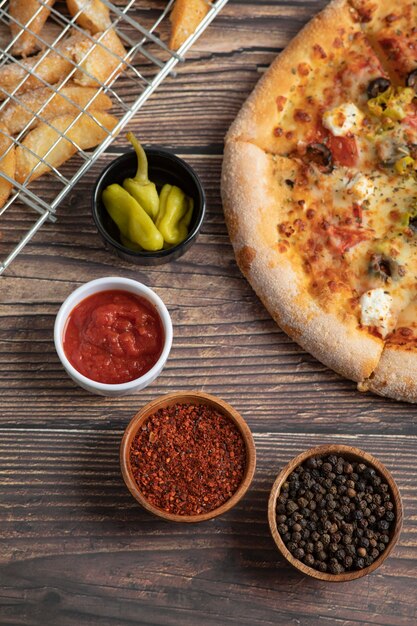 Deliciosa pizza com azeitonas e batata frita em uma mesa de madeira.