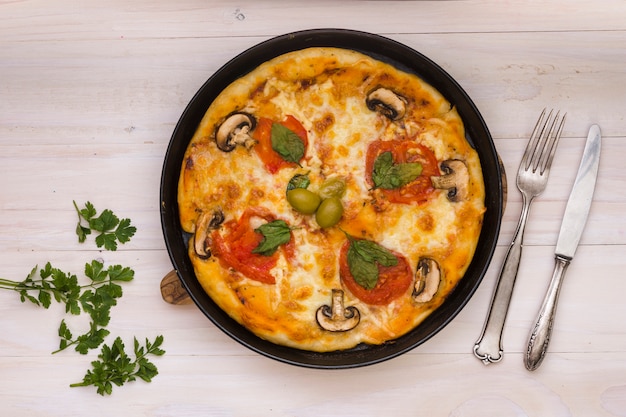 Deliciosa pizza com tomate e cogumelos frescos e azeitonas em fundo de madeira