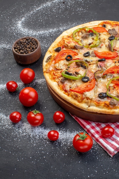 Deliciosa pizza de queijo com tomate vermelho em uma superfície escura com vista frontal