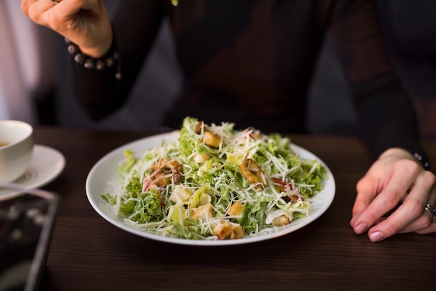 Deliciosa salada com croutons; camarão e queijo parmesão ralado na mesa na frente de uma pessoa